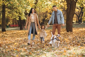 Happy young family walks and plays with a dog in the autumn park
